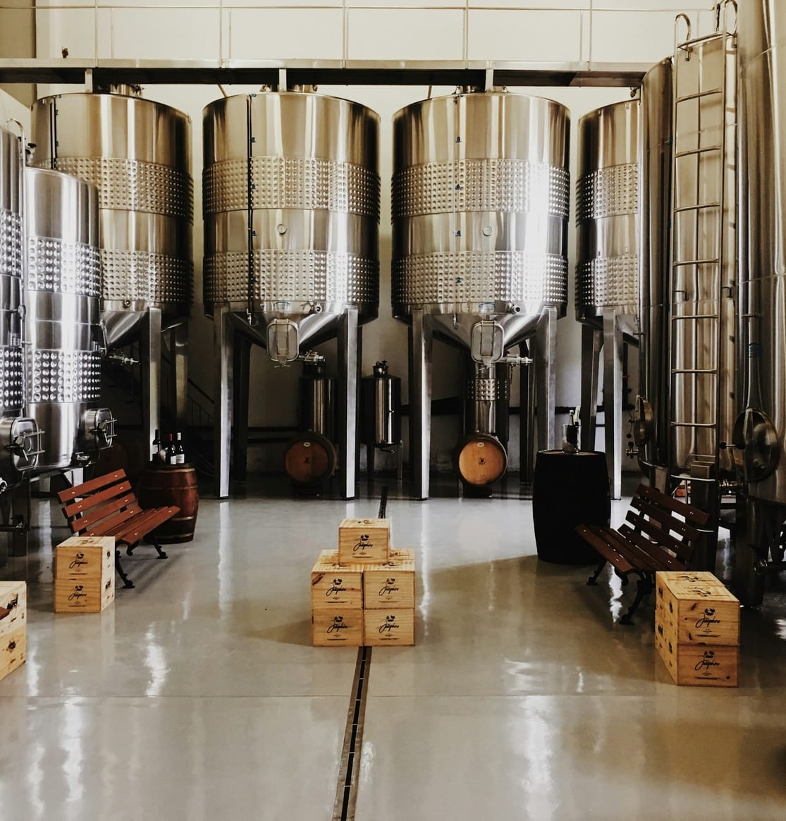 Stainless steel fermentation tanks lined up in a drinks production hall